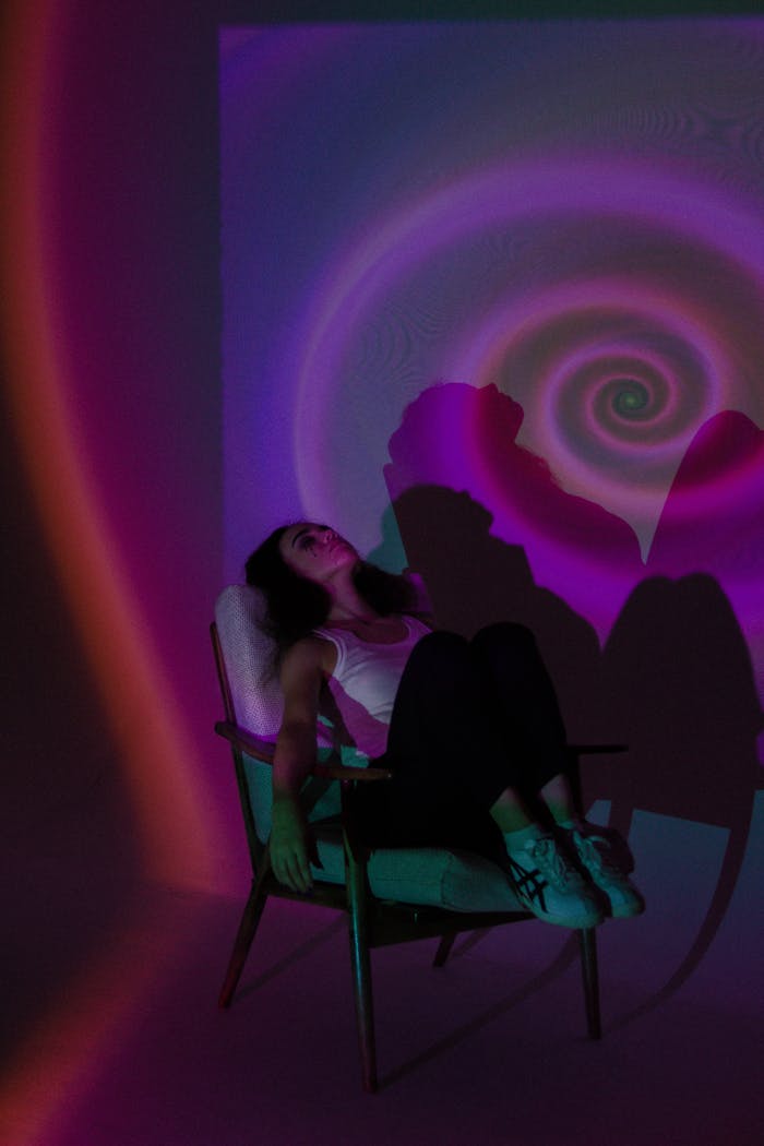 portfolio-img-01 A woman sitting in an armchair with colorful swirling lights creating a psychedelic background.